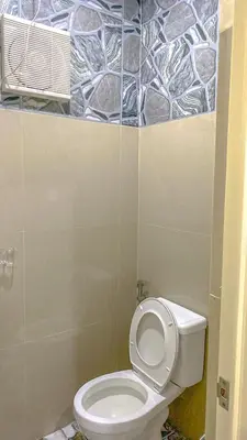 a bathroom with a toilet and a tile wall at FACE Transient Rooms in Kawit