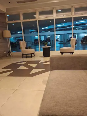 a lobby with two chairs and tables in a building at Affordable Stay near BGC, Makati in Manila