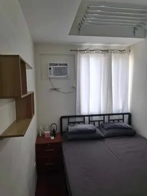 a bedroom with a bed and a window with white curtains at Affordable Stay near BGC, Makati in Manila