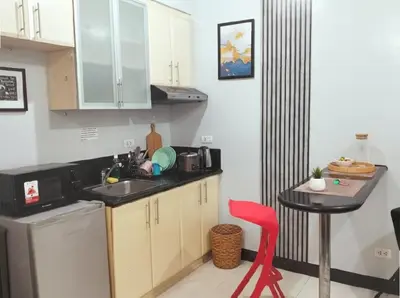 a small kitchen with a sink and a red chair at BGC McKinley Apartment B1 in Manila