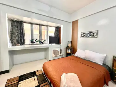 a bedroom with a bed and a window at BGC McKinley Apartment B1 in Manila