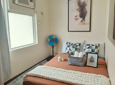 a bedroom with a bed with a window and a fan at Cozy Home in BGC McKinley B2 in Manila