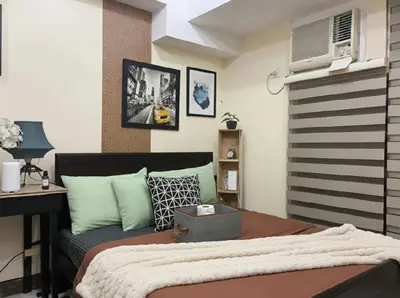 a bedroom with a bed and a desk and a computer at Cozy Home in BGC McKinley B2 in Manila