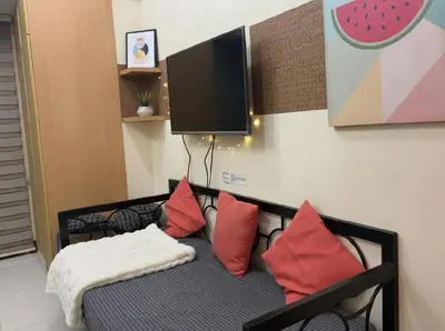 a room with a chair with pillows and a tv at Heart of BGC McKinley B3 in Manila
