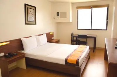 a bedroom with a bed and a table and a window at M Suites Hotel in Manila