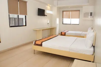 a bedroom with two beds and a television in it at M Suites Hotel in Manila