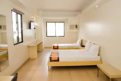 a hotel room with two beds and a window at M Suites Hotel in Manila