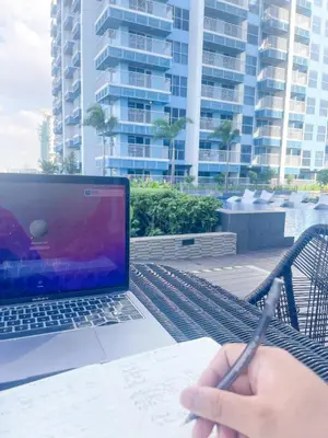 a person writing on a piece of paper next to a laptop at Modern Luxury 4BR Manila Bay beside Okada Manila in Manila