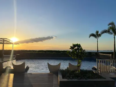 a view of a pool with chairs and a sunset at Luxurious 3BR in Manila Bay beside Okada in Manila