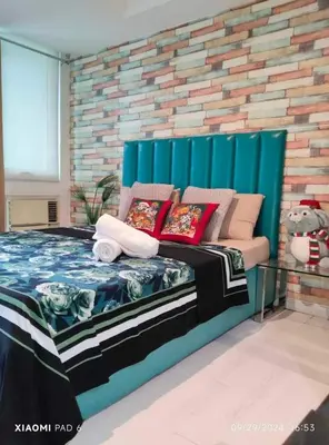 a bedroom with a bed with a blue head board at 225 St Tropez Tower Azure Urban Resort Residences in Manila