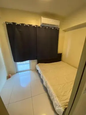 a small bedroom with a bed and a black curtain at Breeze Residences 26th floor in Manila