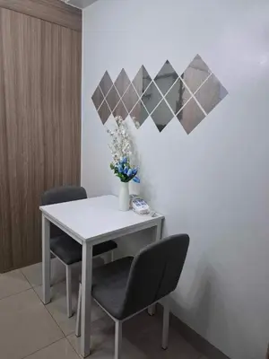 a white table with two chairs and a vase with flowers at Shore2 Residences in Manila