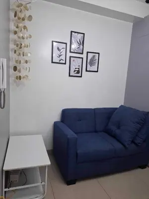 a blue couch in a living room with pictures on the wall at Shore2 Residences in Manila