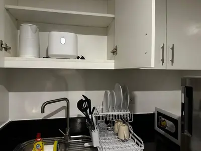 a kitchen with a sink and a dish rack with utensils at 1BR Stay near NAIA Terminal 3 via Runway Manila in Manila
