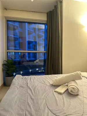 a bed with two towels on it with a window at Bayshore 2 Residential Resort Phase 1 in Manila