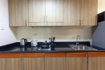 a kitchen with a sink and wooden cabinets at Shore Residences Family Suite near MOA 1 Bedroom with Balcony - 3beds good for 6 person in Manila