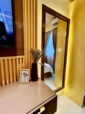a bathroom with a mirror and a vase with flowers on a counter at Crib2Go Lupita Suite with City Street View in Manila