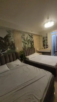 a bedroom with two beds and a wall with plants at Plete's Suite in Manila