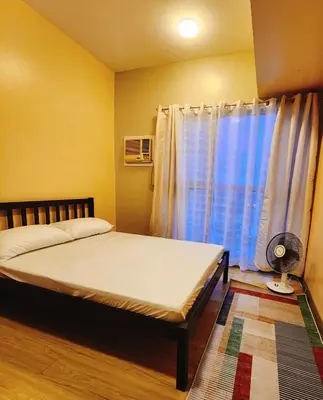 a bedroom with a bed and a window with a fan at Furnished 2Bedroom 2Bathroom plus Utility Room with 2 Beds in Manila