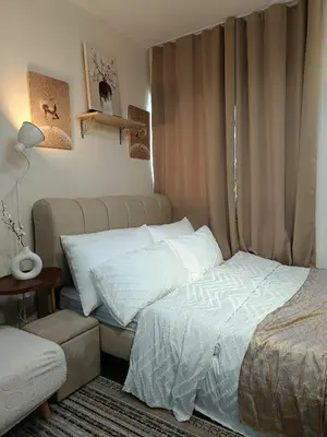 a bedroom with a bed and a chair next to a window at Miranda's Suite by Fullerton in Silang