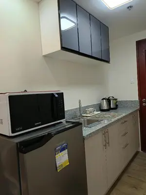 a kitchen with a microwave on top of a refrigerator at Miranda's Suite by Fullerton in Silang