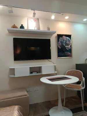 a living room with a tv and a white table at Miranda's Suite by Fullerton in Silang