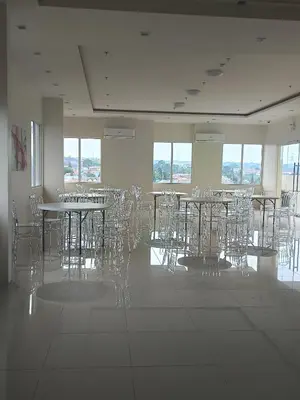 an empty room with tables and chairs and windows at Miranda's Suite by Fullerton in Silang