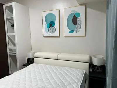 a bedroom with a bed and two pictures on the wall at Queen size bed at Air Ayala Ave Makati in Manila