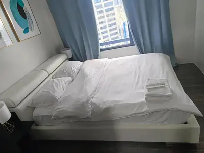 a bed with white sheets in a room with a window at Queen size bed at Air Ayala Ave Makati in Manila