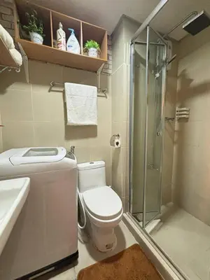 a bathroom with a toilet and a glass shower at El Romantico Staycation at Fame Residence in Manila
