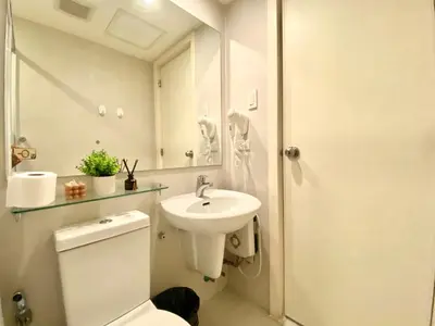 a bathroom with a toilet and a sink and a mirror at Azure Urban Resort by Melrose Avenue in Manila