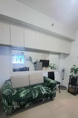 a living room with a green couch and a kitchen at Searendipity - Sea Residences, Pasay City in Manila