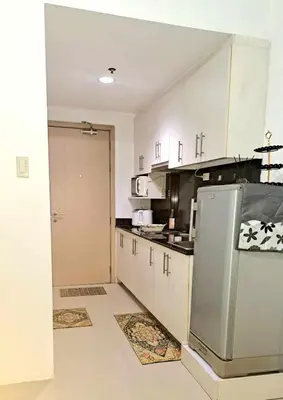 a kitchen with white cabinets and a stainless steel refrigerator at Searendipity - Sea Residences, Pasay City in Manila