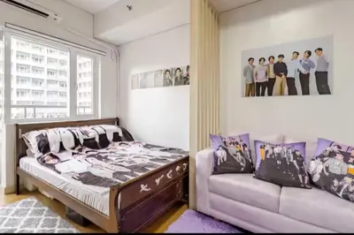 a bedroom with a bed and a couch at House of Bangtan at Grace Residences, Taguig in Manila