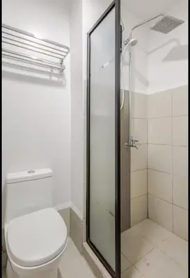 a bathroom with a toilet and a glass shower at House of Bangtan at Grace Residences, Taguig in Manila