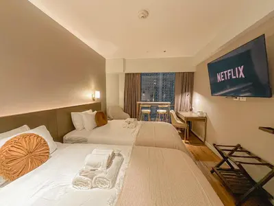 a hotel room with two beds and a television on the wall at Rockwell View Twin Suite with FREE WiFi Pool & Gym in Manila