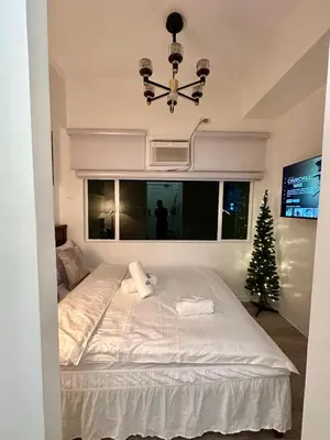 a bedroom with a large white bed with a christmas tree at Studio Two Condominium - Alabang, BLK - Northgate Cyberzone, Filinvest City, Alabang - Netflix-ready Fiber Wi-Fi in Manila
