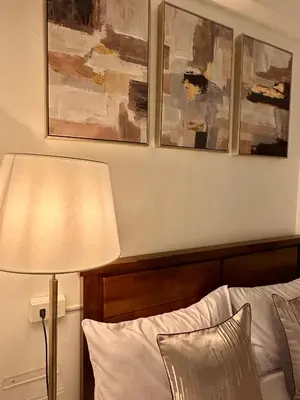 a bedroom with a bed with a lamp and three paintings at Studio Two Condominium - Alabang, BLK - Northgate Cyberzone, Filinvest City, Alabang - Netflix-ready Fiber Wi-Fi in Manila