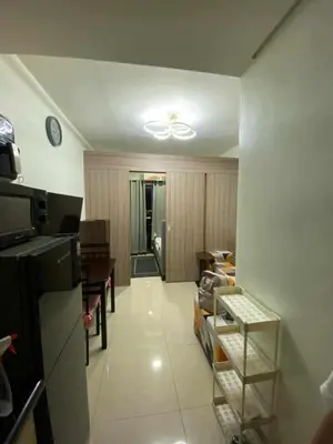 a living room with a ceiling fan and a kitchen at Shore Residences in Manila