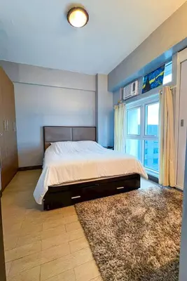 a bedroom with a bed and a large window at Le Grand one in Manila