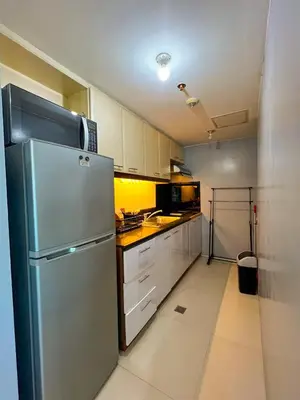 a kitchen with a stainless steel refrigerator and white cabinets at Le Grand one in Manila