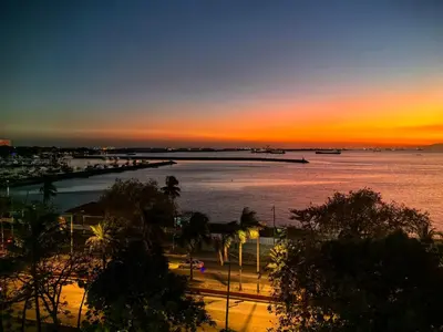 a sunset over a body of water with a pier at Vincondotel Roxas Ave Manila 1BR Marbella in Manila
