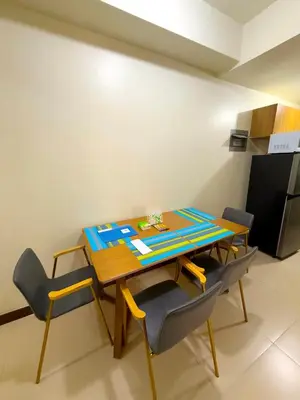 a dining room table with four chairs and a refrigerator at Vincondotel Near BGC 2BR Fairlane in Manila