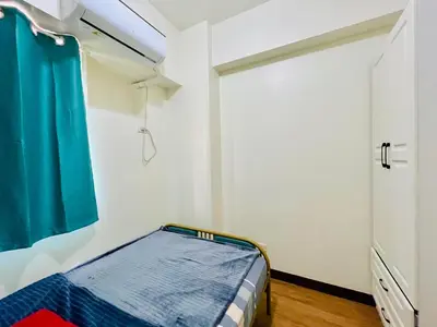 a small bedroom with a bed and a door at Fairlane Residences in Manila
