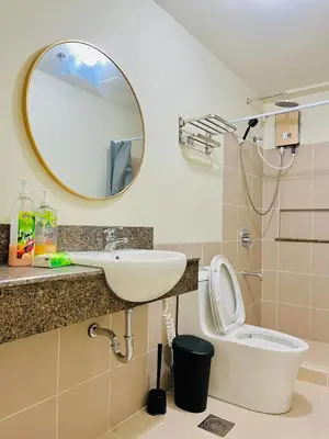 a bathroom with a sink and a mirror and a toilet at Fairlane Residences in Manila