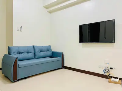 a blue couch in a room with a tv on a wall at Fairlane Residences in Manila