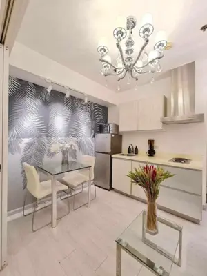 a kitchen with a glass table and a chandelier at Azure Urban Residences by Lyn in Manila