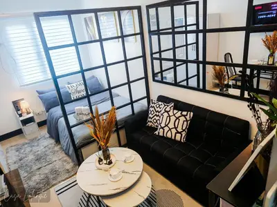 a living room with a black couch and a table at Casa Lolanthe Fully Furnished Studio Unit in Pasong Bayog