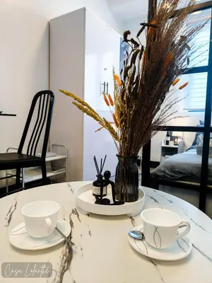 a table with two cups and a vase with flowers at Casa Lolanthe Fully Furnished Studio Unit in Pasong Bayog