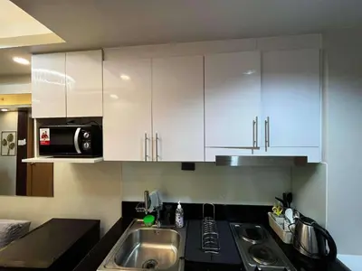 a kitchen with white cabinets and a sink at Stylish and Modern Suite with Pool Access and Parking in Manila